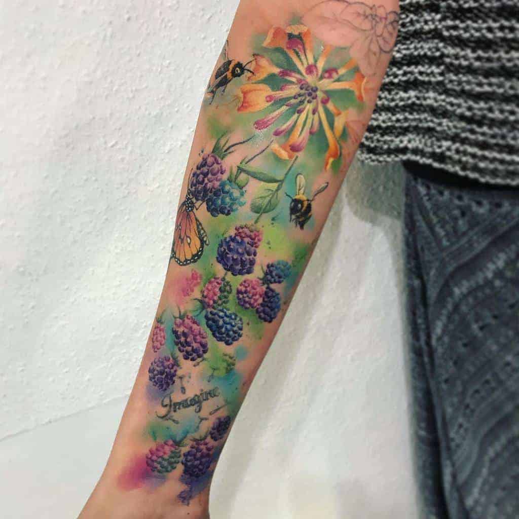 Colorful forearm tattoo of blackberries, flowers, bees, and a butterfly with a watercolor background and "Imagine" text