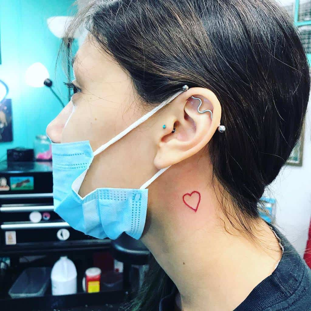 Woman with a red heart tattoo behind their ear