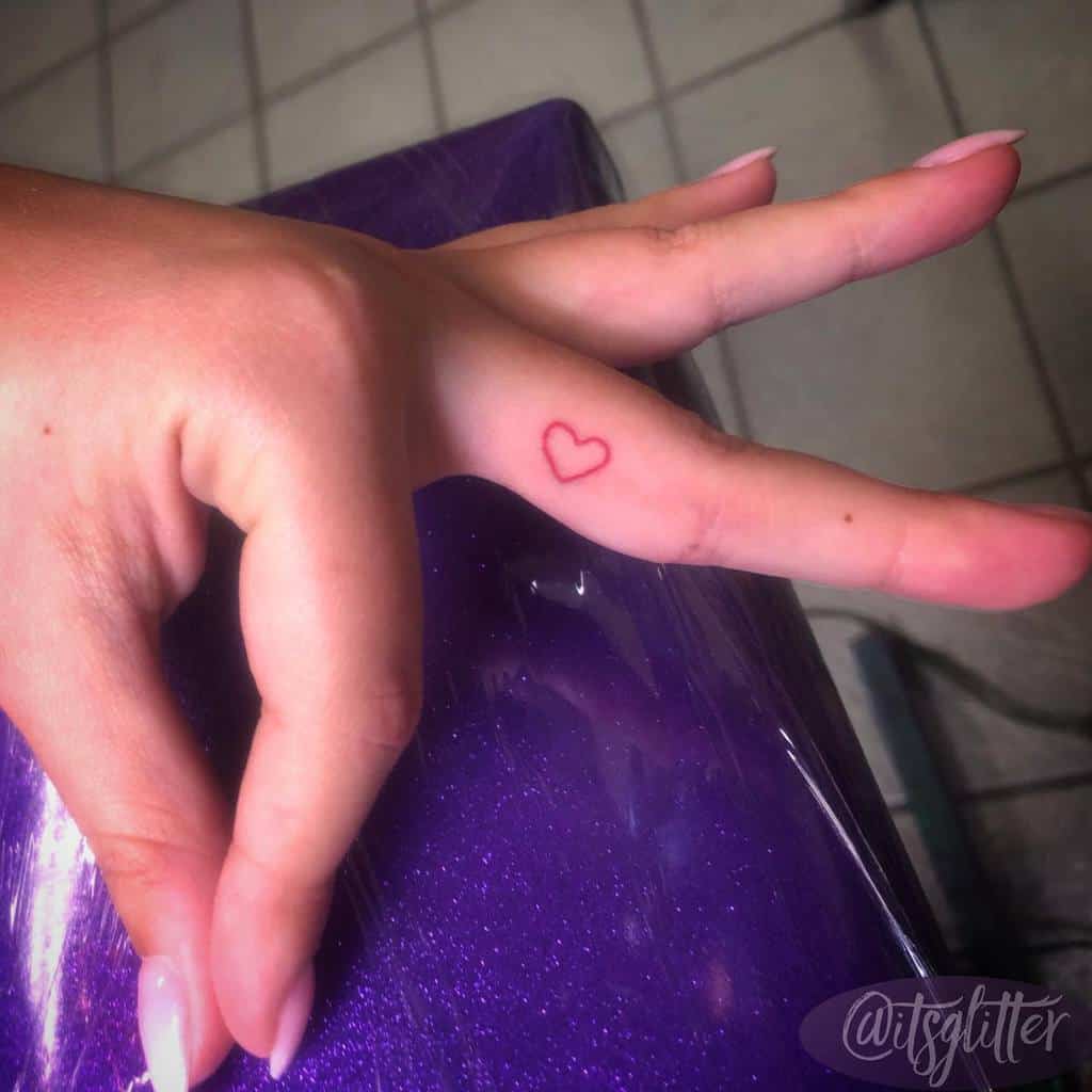 Red heart outline tattoo on the middle finger