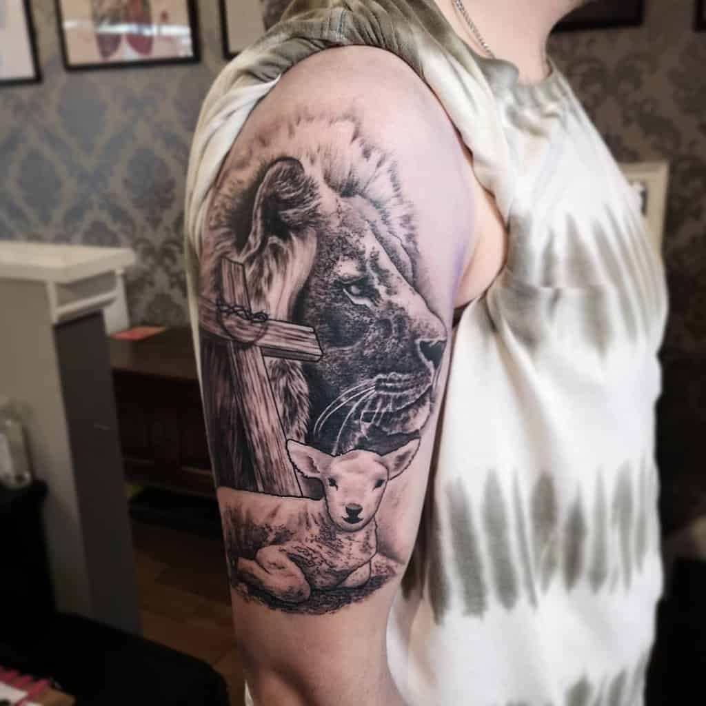 Tattoo of a majestic lion and lamb alongside a cross on a person's upper arm
