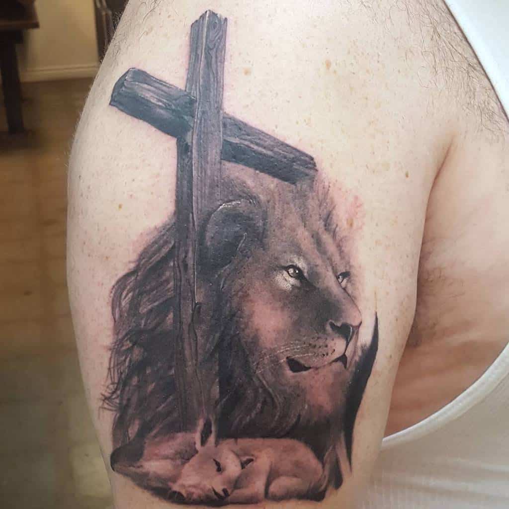 Tattoo of a majestic lion, gentle lamb, and wooden cross on an upper arm