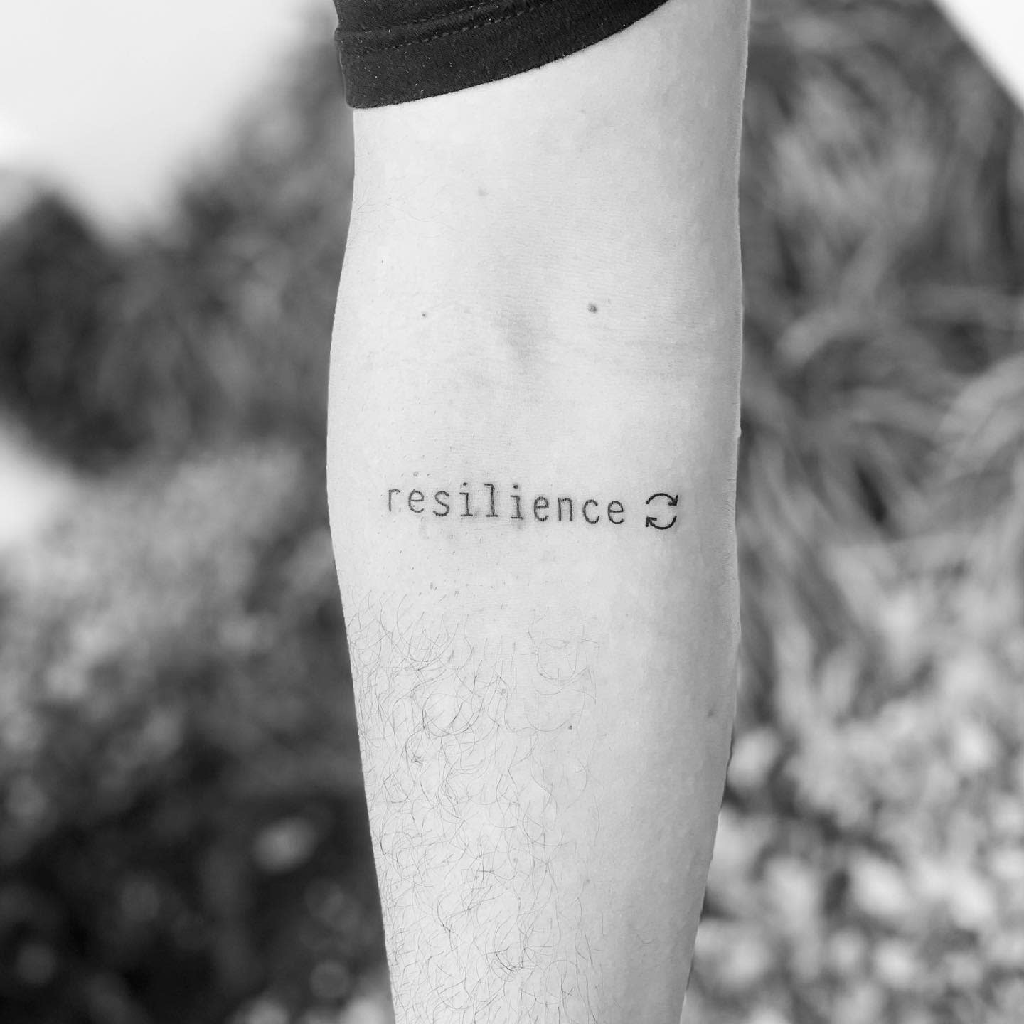 Forearm tattoo with the word "resilience" and an infinity symbol