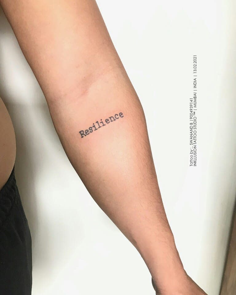 Tattooed arm with the word "Resilience" on the inner forearm