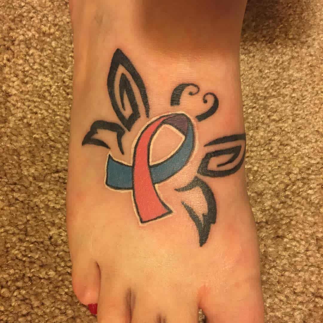 A tattoo of a butterfly with a pink and blue ribbon on the top of a foot