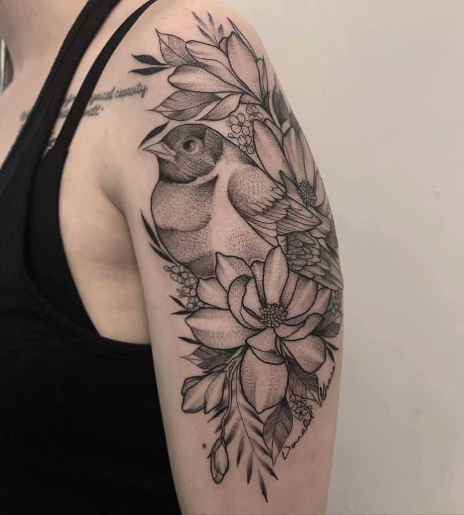 Tattoo of a robin surrounded by flowers and leaves in black ink