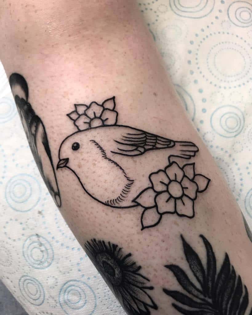 Black ink outline tattoo of a robin surrounded by two small flowers and leaves, featuring a simple and clean traditional design without shading