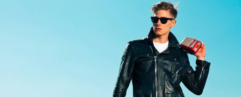 Man dressed in a rockabilly style wearing a leather jacket and sunglasses