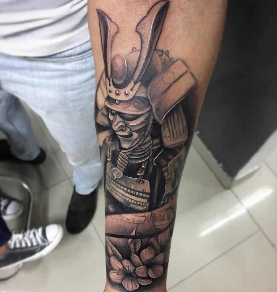 Intricate samurai Ronin tattoo on the forearm, featuring a detailed helmet, armor, and cherry blossoms for a balanced design