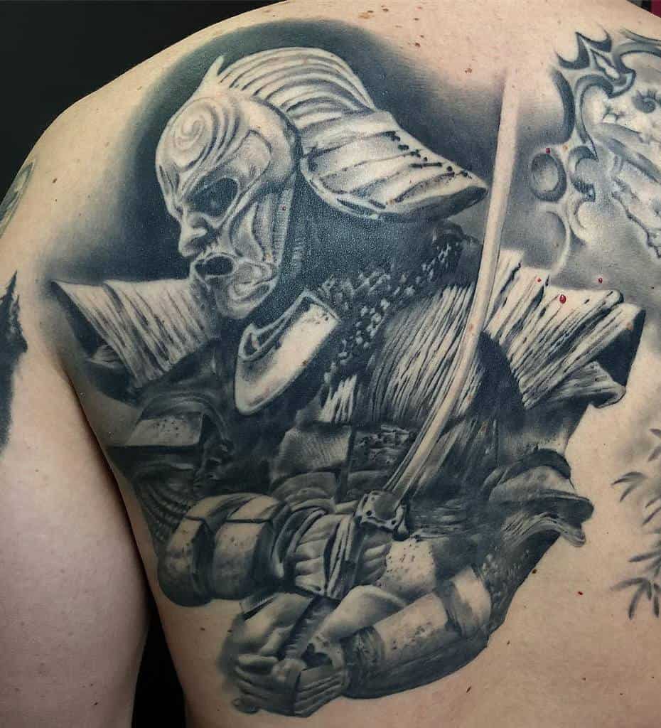 Intense black and gray back tattoo of a Ronin wearing detailed armor and a fearsome mask, wielding a katana in a battle-ready pose