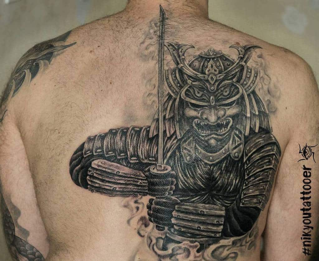 Bold back tattoo featuring a menacing samurai in detailed armor holding a katana, surrounded by swirling smoke effects