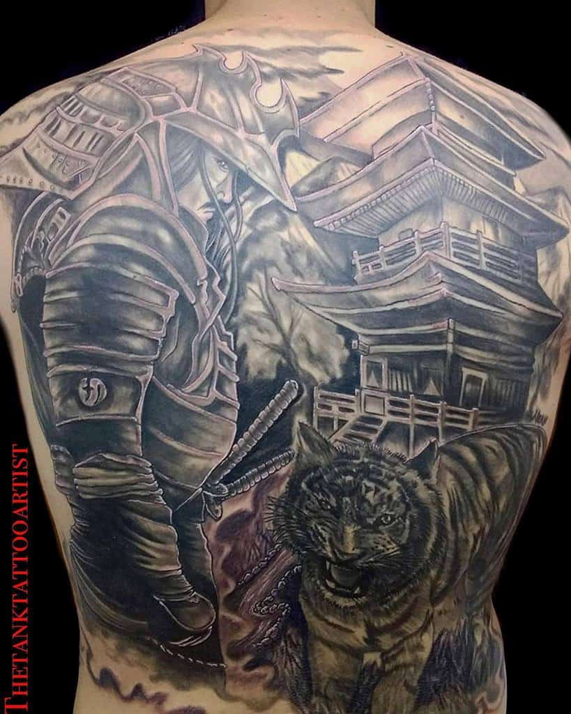 Elaborate full-back tattoo featuring a samurai in detailed armor, a fierce tiger, and a traditional Japanese temple amidst a dramatic landscape