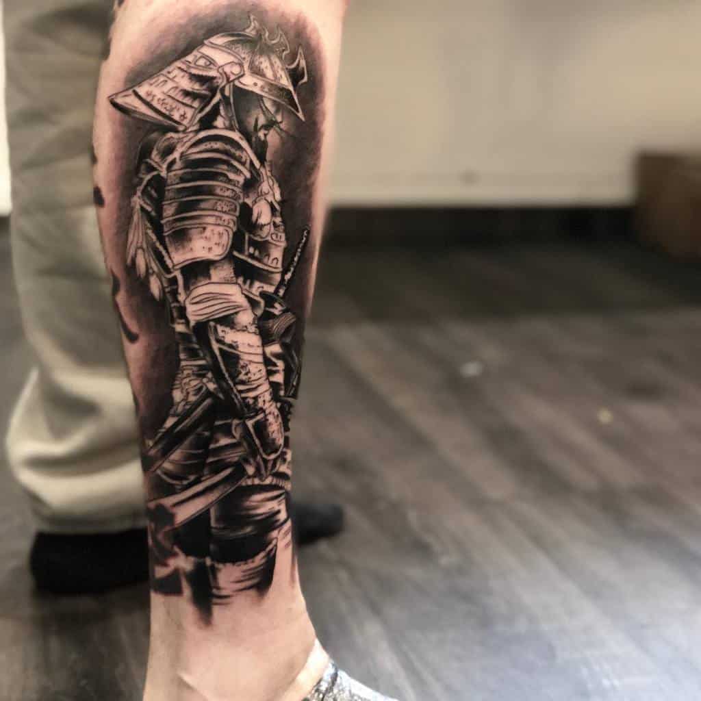 Detailed black and grey leg tattoo featuring a samurai in full armor, showcasing intricate textures and shading, evoking a sense of tradition and discipline