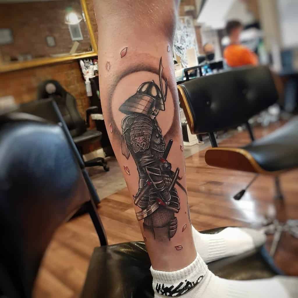 Intricate leg tattoo featuring a lone samurai (Ronin) in armor with cherry blossom petals and a circular backdrop for a bold look