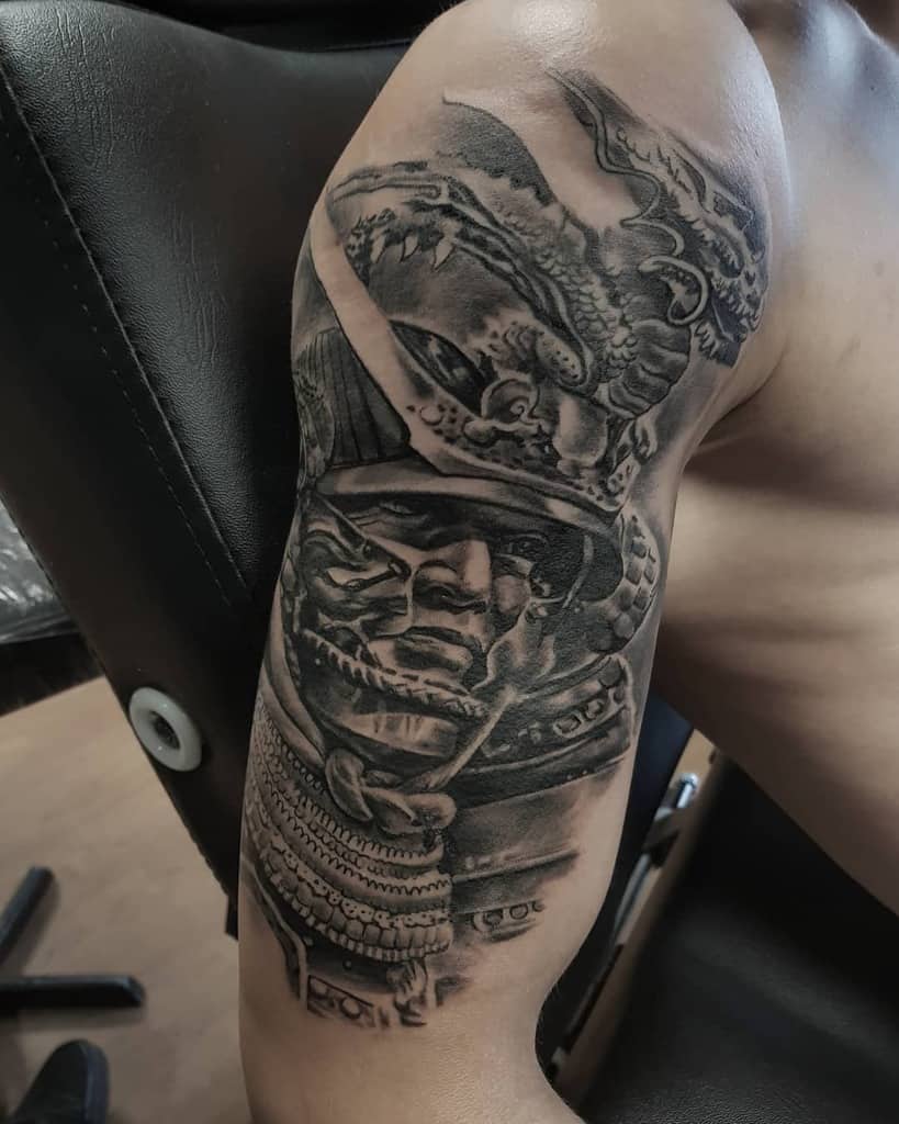Intricate black-and-gray tattoo featuring a fierce samurai warrior with detailed armor, a dramatic dragon, and intense shading for a striking design