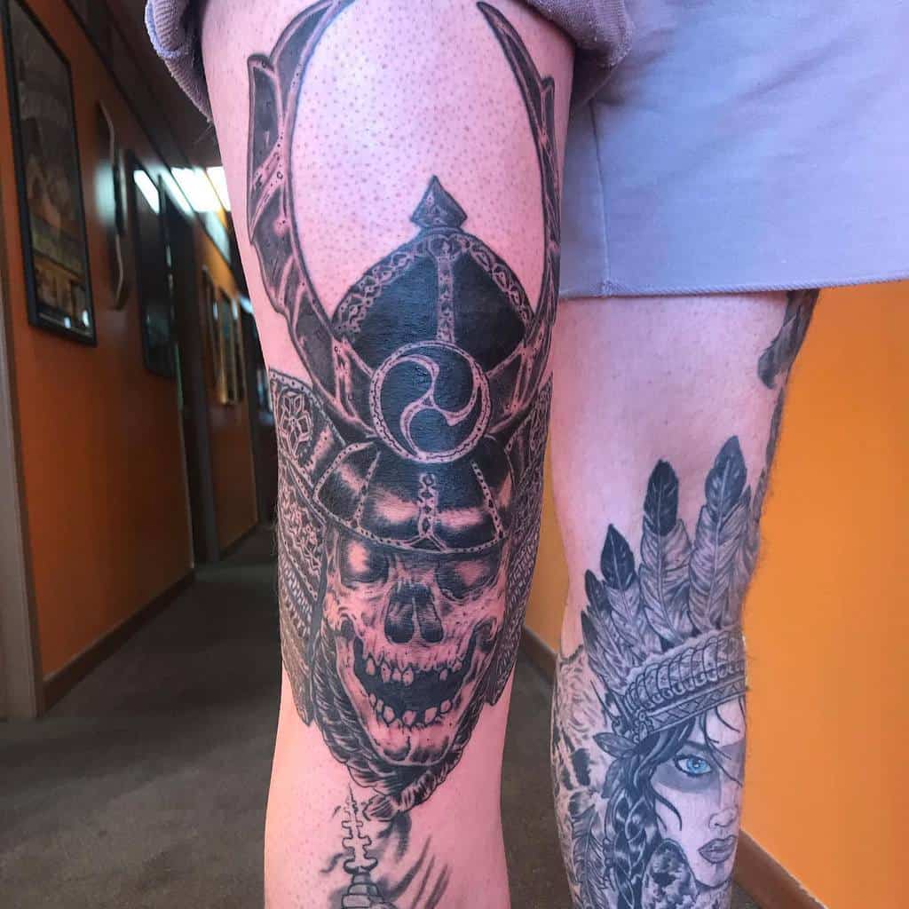 A striking samurai skull tattoo on the thigh with detailed armor and strong contrasts, creating a bold and fierce look