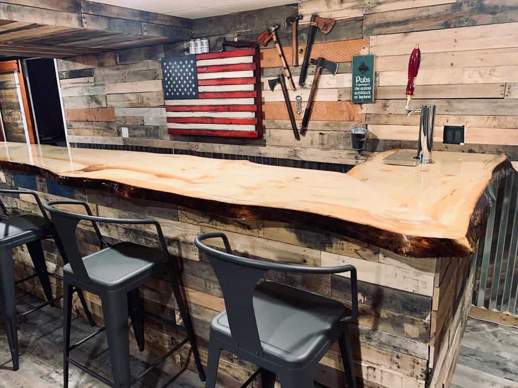 Rustic bar with live edge wood countertop, metal stools, and American flag wall decor.