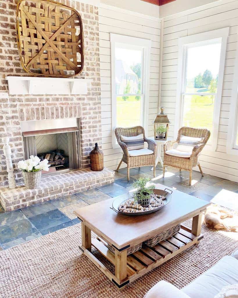 small sunroom with brick fireplace and wicker chairs