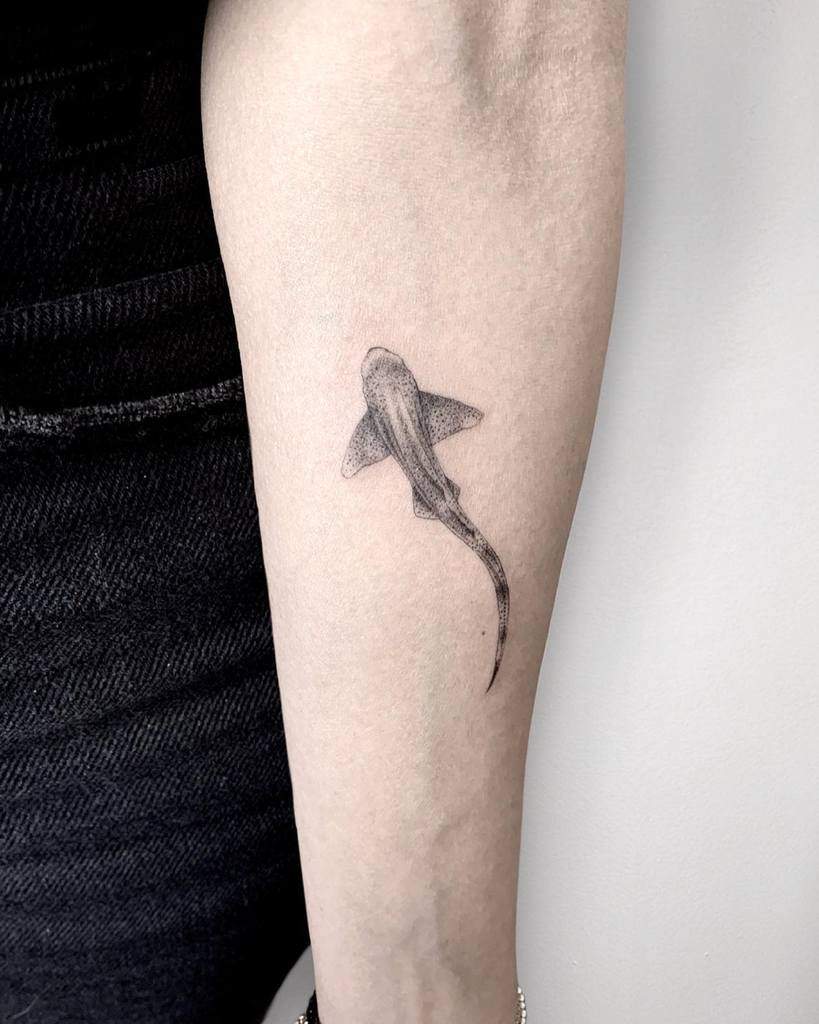 A single needle tattoo of a shark on a forearm displaying intricate details and precision