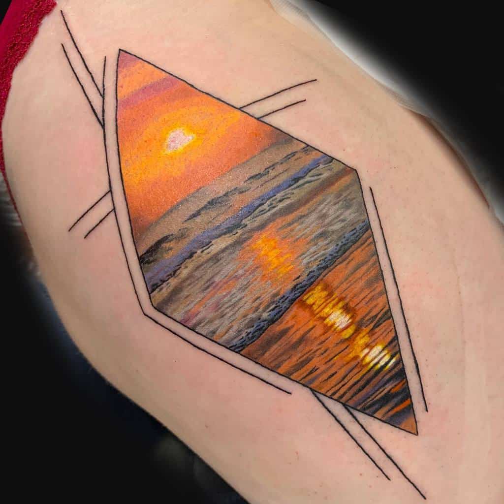Vibrant tattoo of a sunset over the ocean, framed within a geometric diamond shape with black line accents, featuring rich orange and blue hues