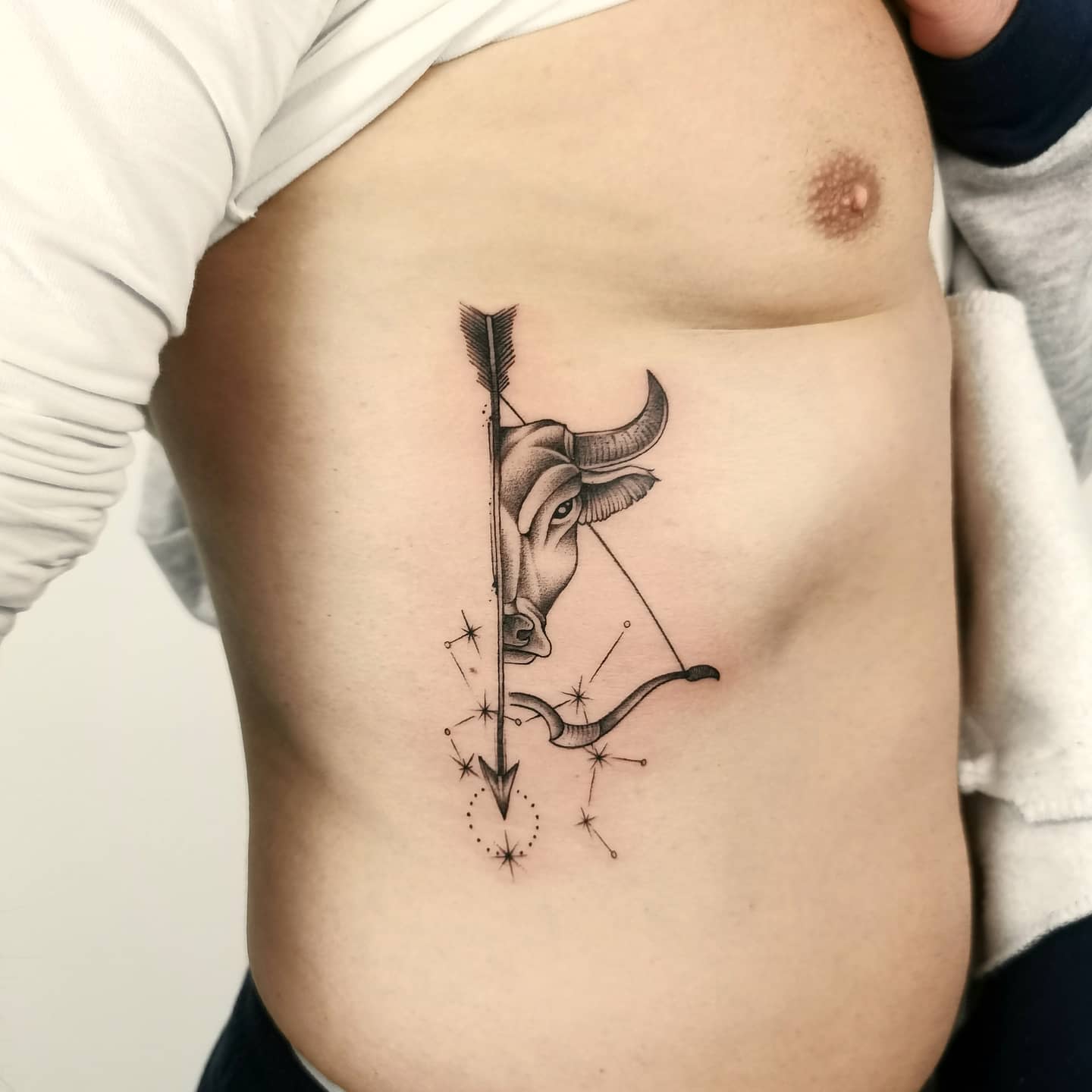Tattoo of bull and arrow with starry constellation on ribcage