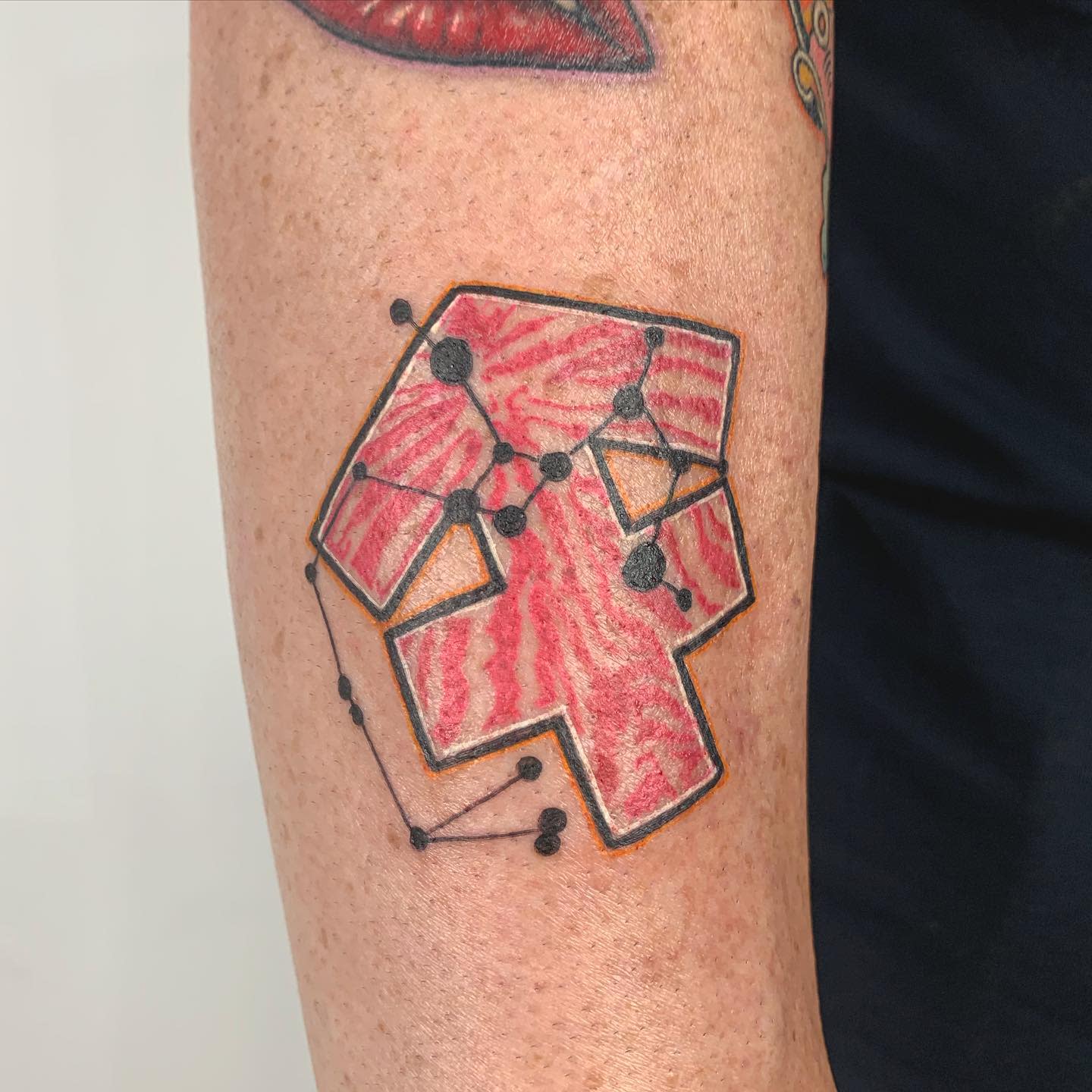 Tattoo of a red geometric shape with Sagittarius constellation on an arm