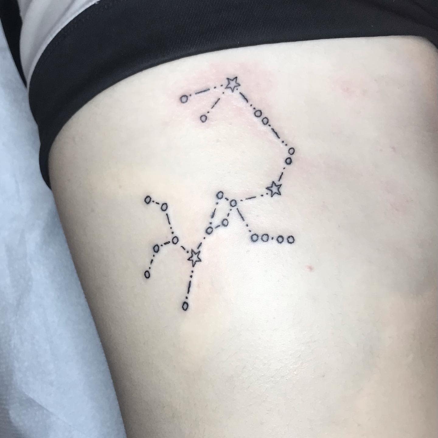 A tattoo of the Scorpio constellation outlined with stars and dots on skin
