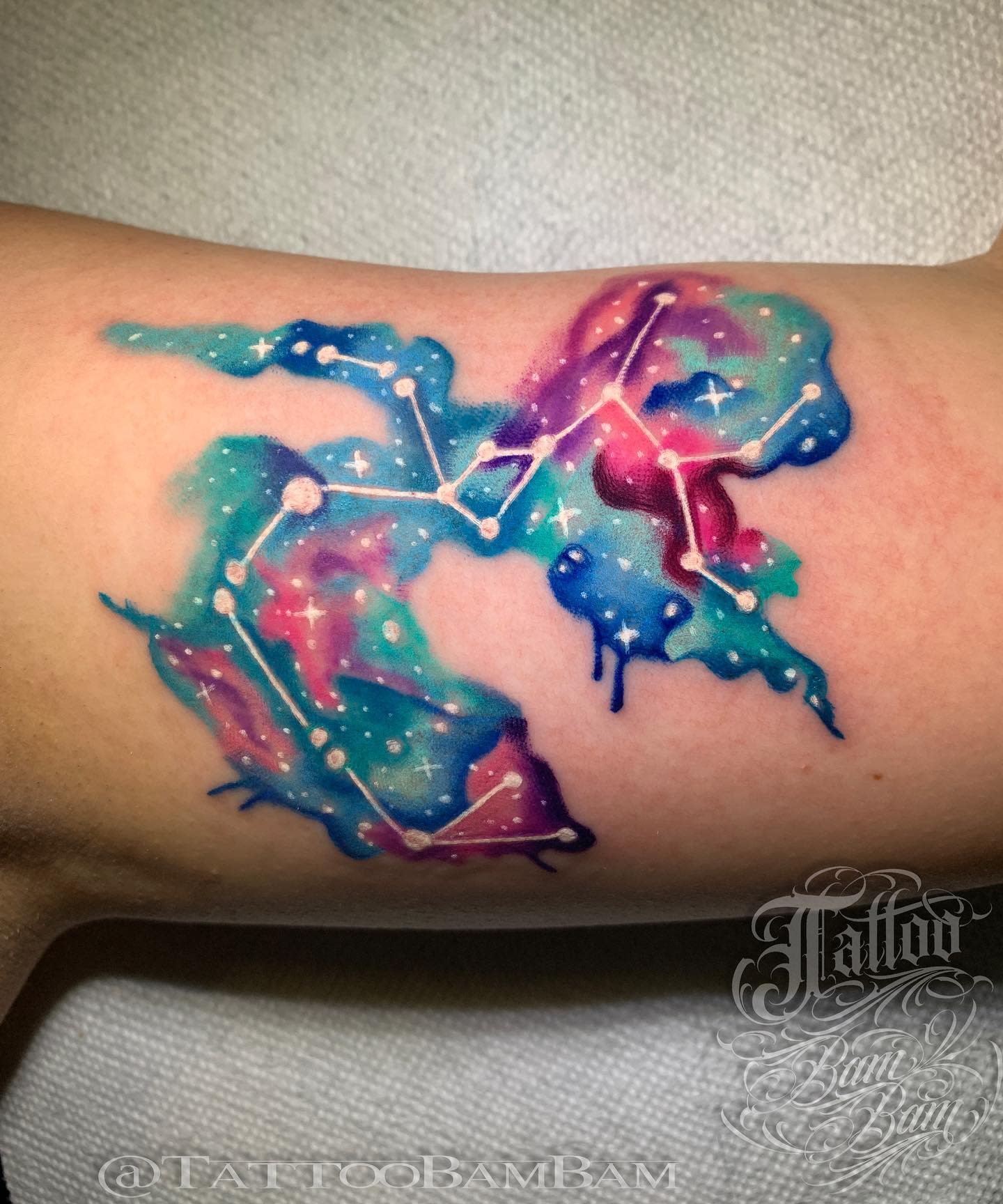 Tattoo of a colorful galaxy with constellations on an arm