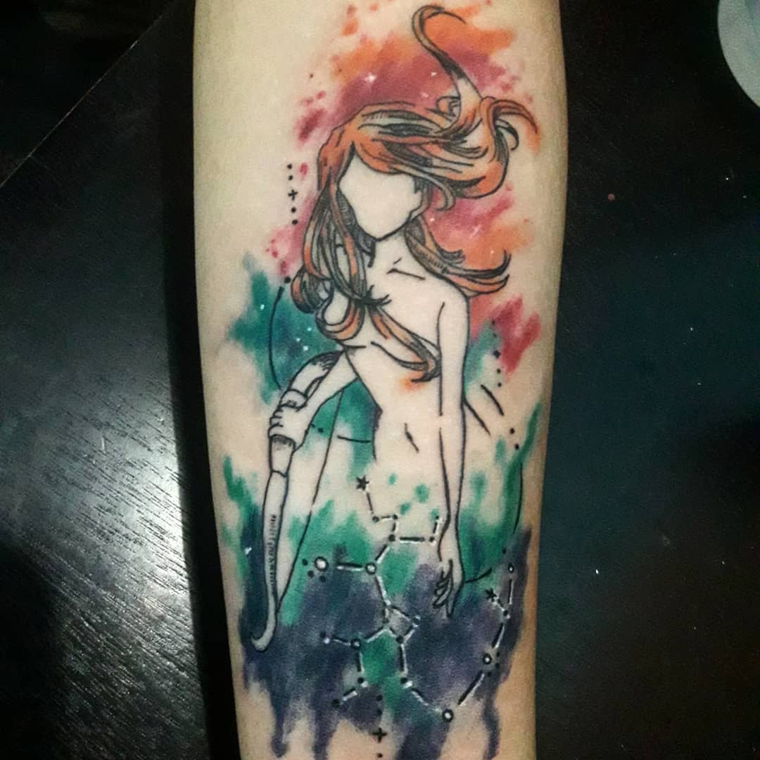A tattoo of a faceless woman with flowing hair and a colorful watercolor background