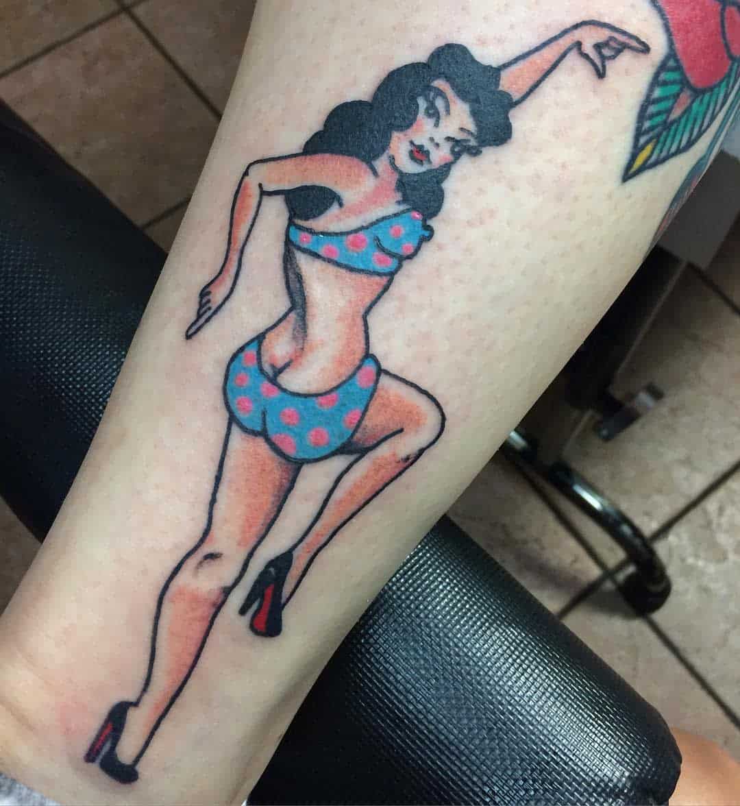 Tattoo of a pin-up style woman in a blue polka dot swimsuit and high heels, posing with one leg raised