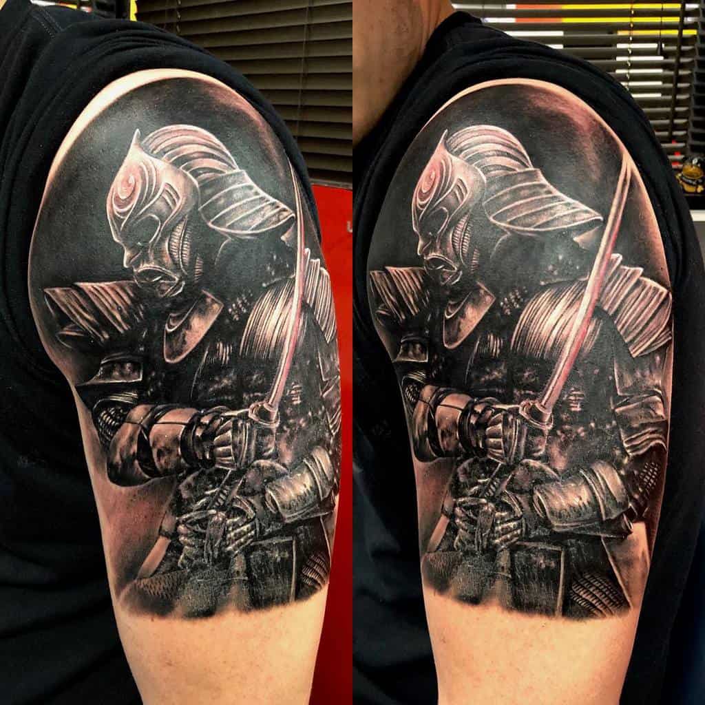 Stunning black-and-gray samurai tattoo with intense shading, showcasing a warrior in full armor holding a katana with dramatic lighting effects