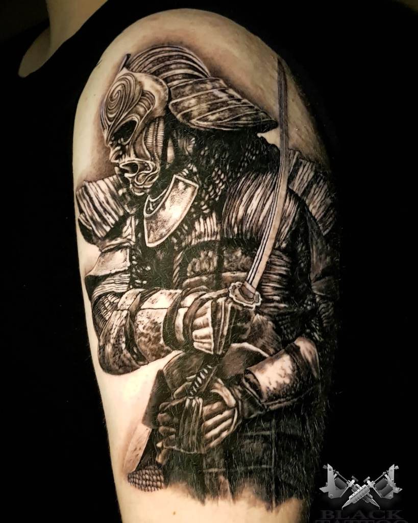 Intricate black-and-gray tattoo of a fierce samurai warrior in full armor, gripping a katana, with detailed shading and dramatic contrast