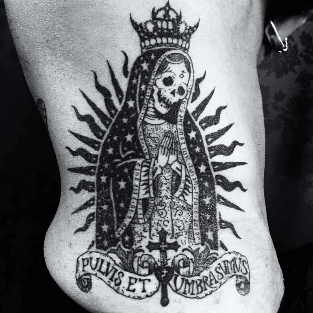 Santa Muerte tattoo with crown and rosary, "Pulvis et Umbra Sumus" text, symbolizing life's fragility