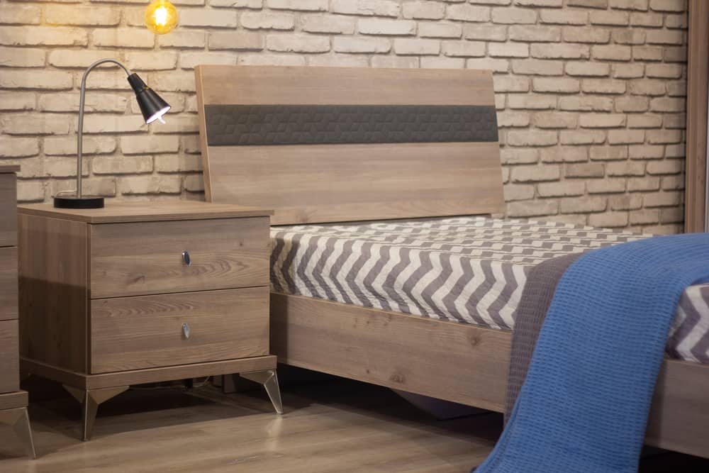 single bed in minimalist bedroom with brick wallpaper