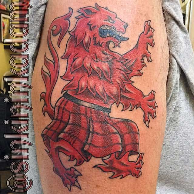 Colorful tattoo of a red Scottish lion in a kilt, standing on hind legs with a fierce expression