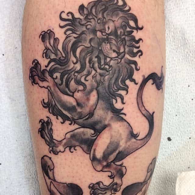 Black ink tattoo of a rampant Scottish lion with detailed mane and tail