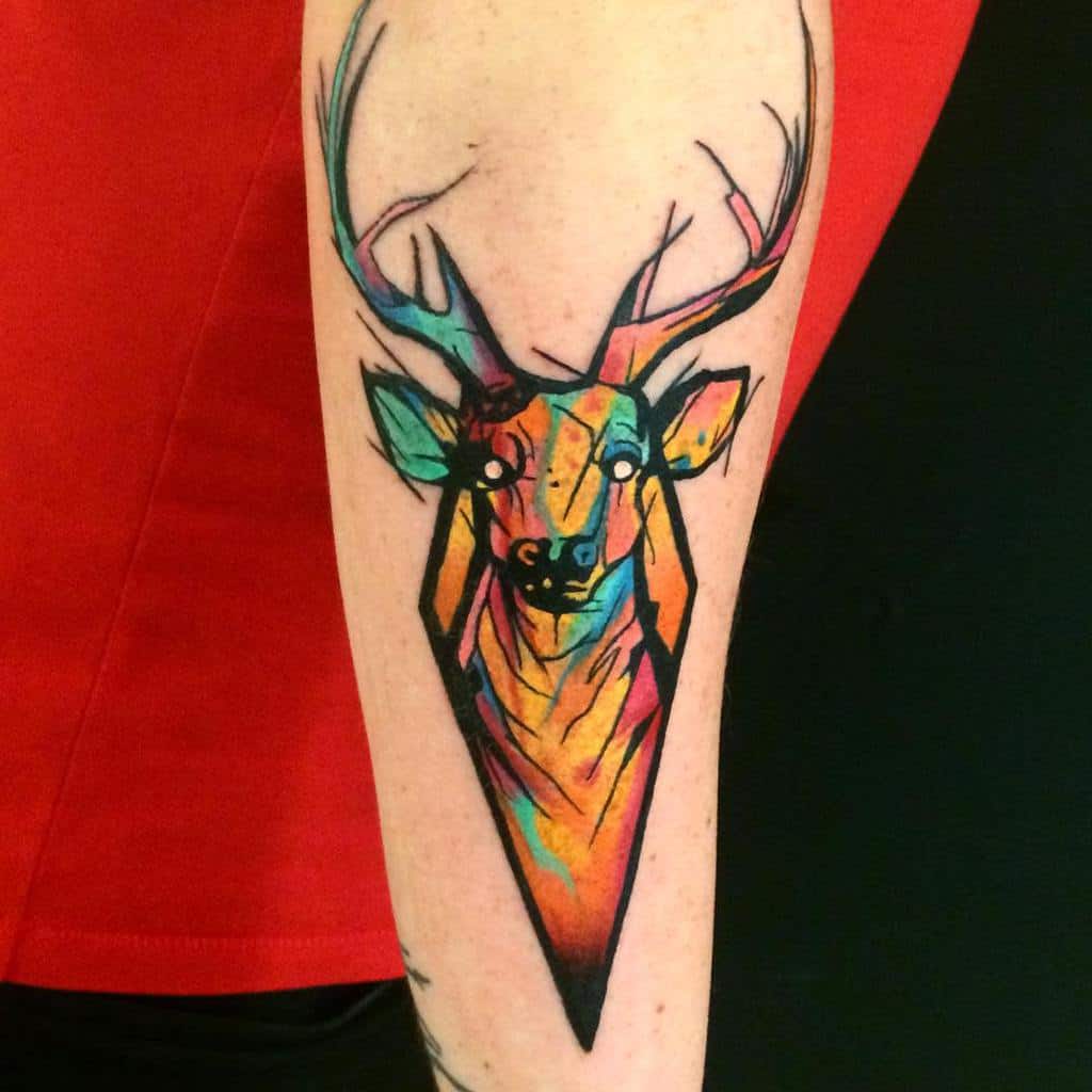 A geometric Scottish stag tattoo with vibrant watercolor shading in blue, orange, and yellow, featuring sharp lines and abstract antlers