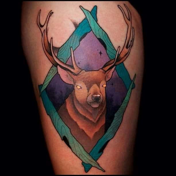Tattoo of a Scottish stag with large antlers in front of a geometric diamond background with green and purple hues