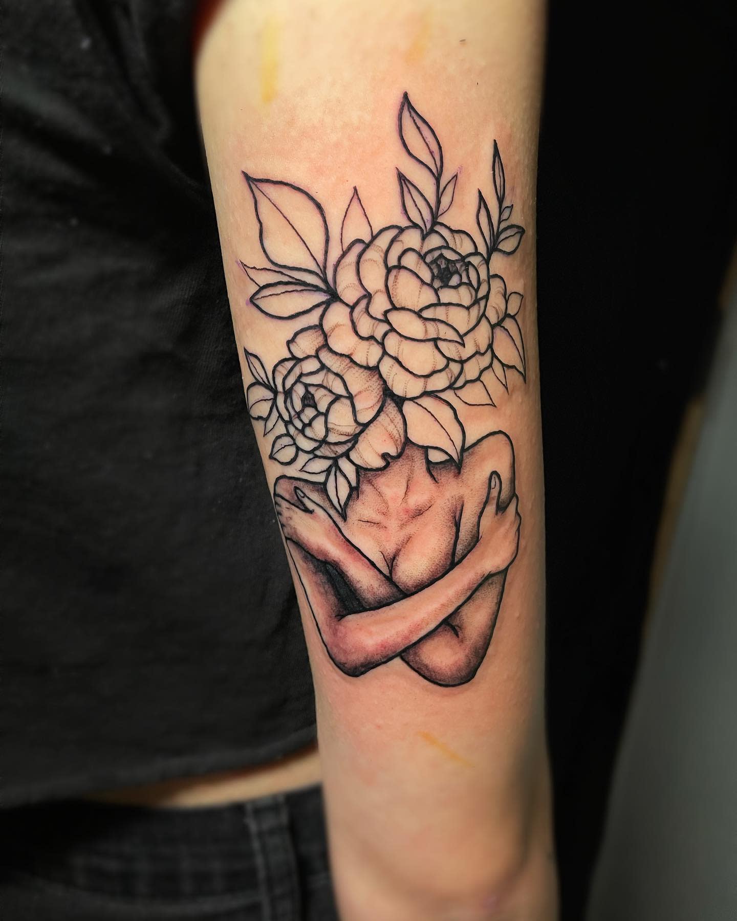 Tattoo of a figure with flower bouquet as head, arms crossed on upper arm