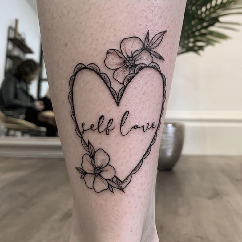 Heart tattoo with flowers and the words "self love" on a leg