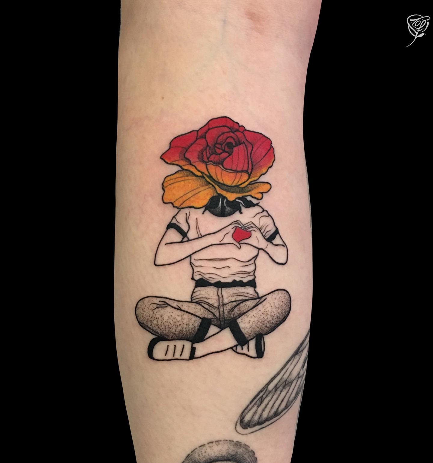 Tattoo of a seated figure with a rose for a head, holding a small red heart