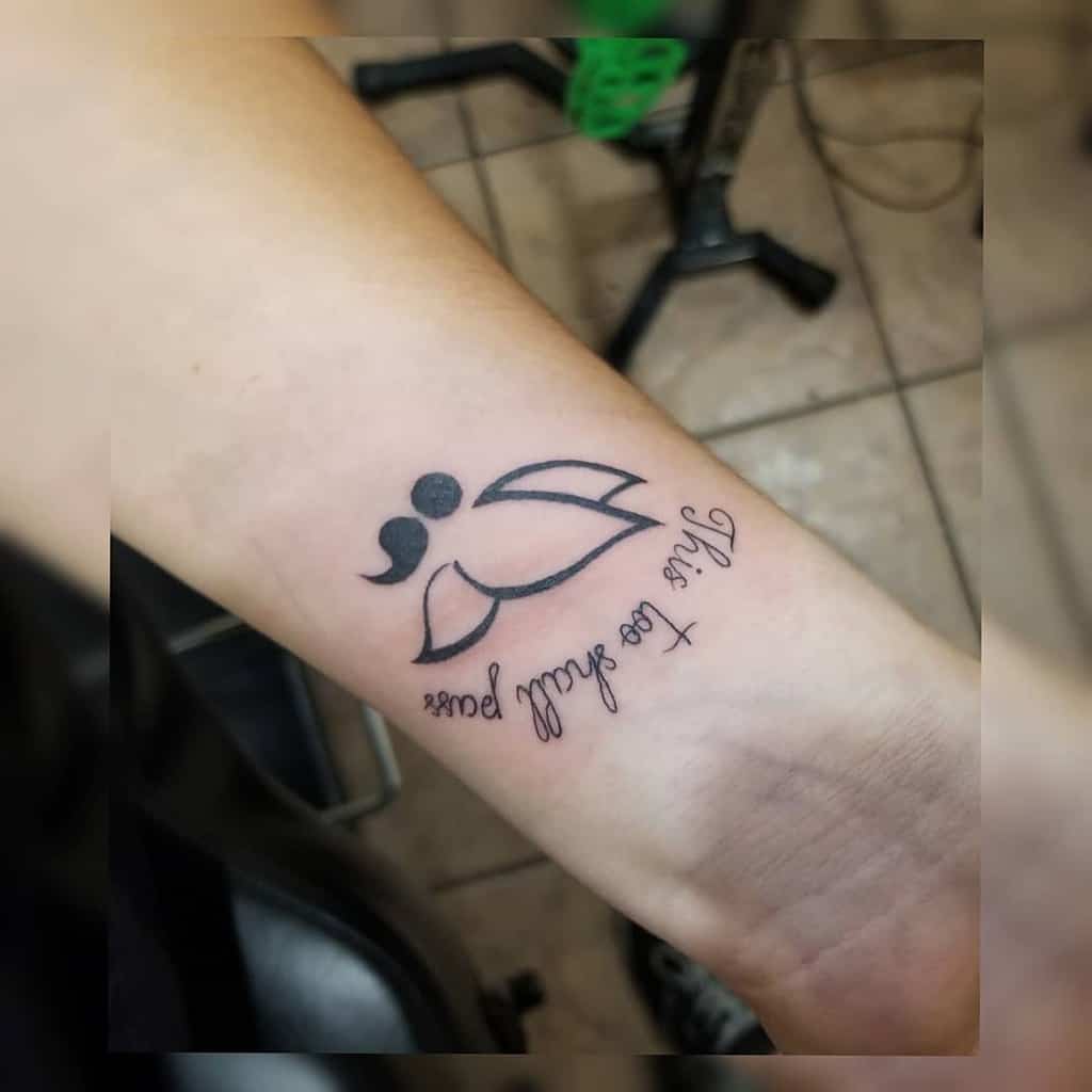 A simple and elegant semicolon butterfly tattoo on the forearm, accompanied by the phrase "This too shall pass," symbolizing hope, resilience, and overcoming personal challenges