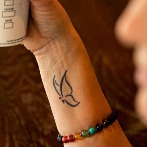 A simple and elegant semicolon butterfly outline tattoo on the wrist, symbolizing resilience, hope, and the power of overcoming challenges with minimalist beauty
