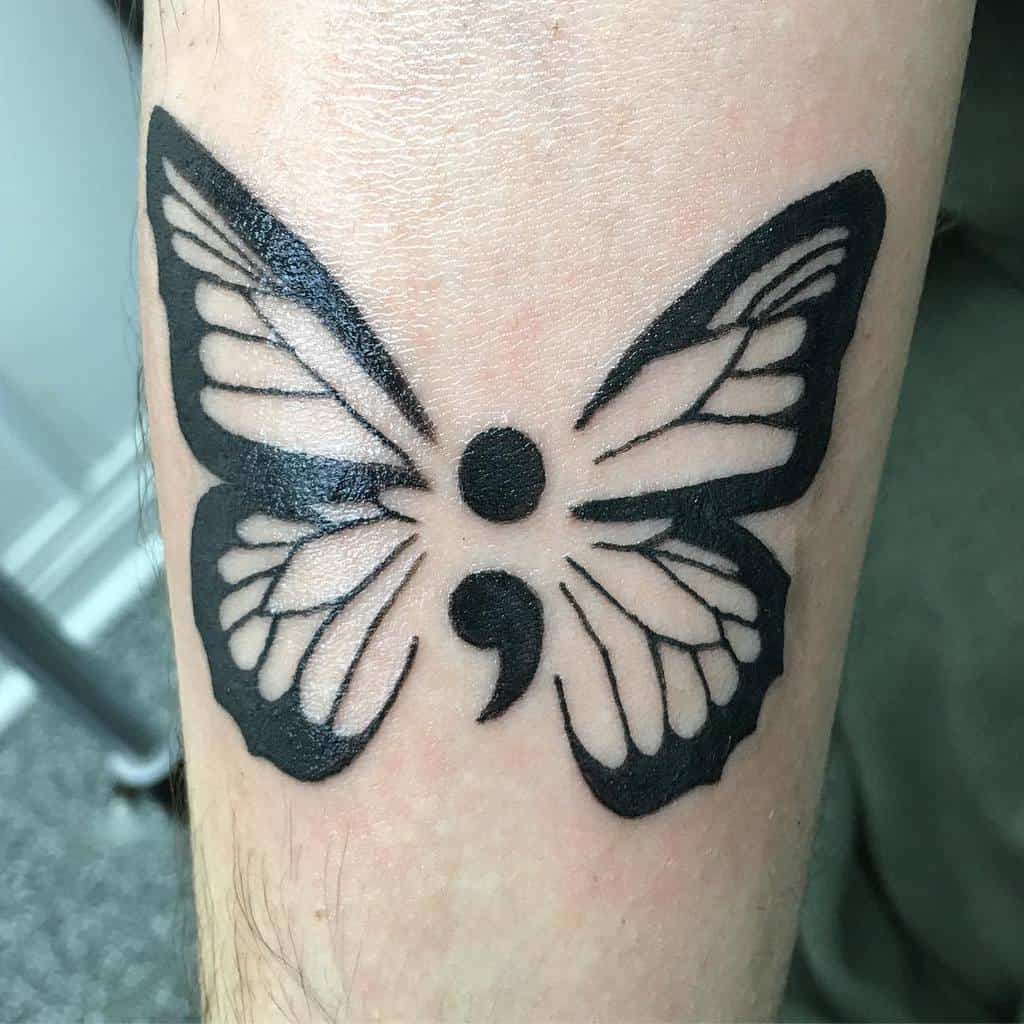 Bold black butterfly tattoo with a semicolon at its center, symbolizing strength, hope, and mental health awareness.
