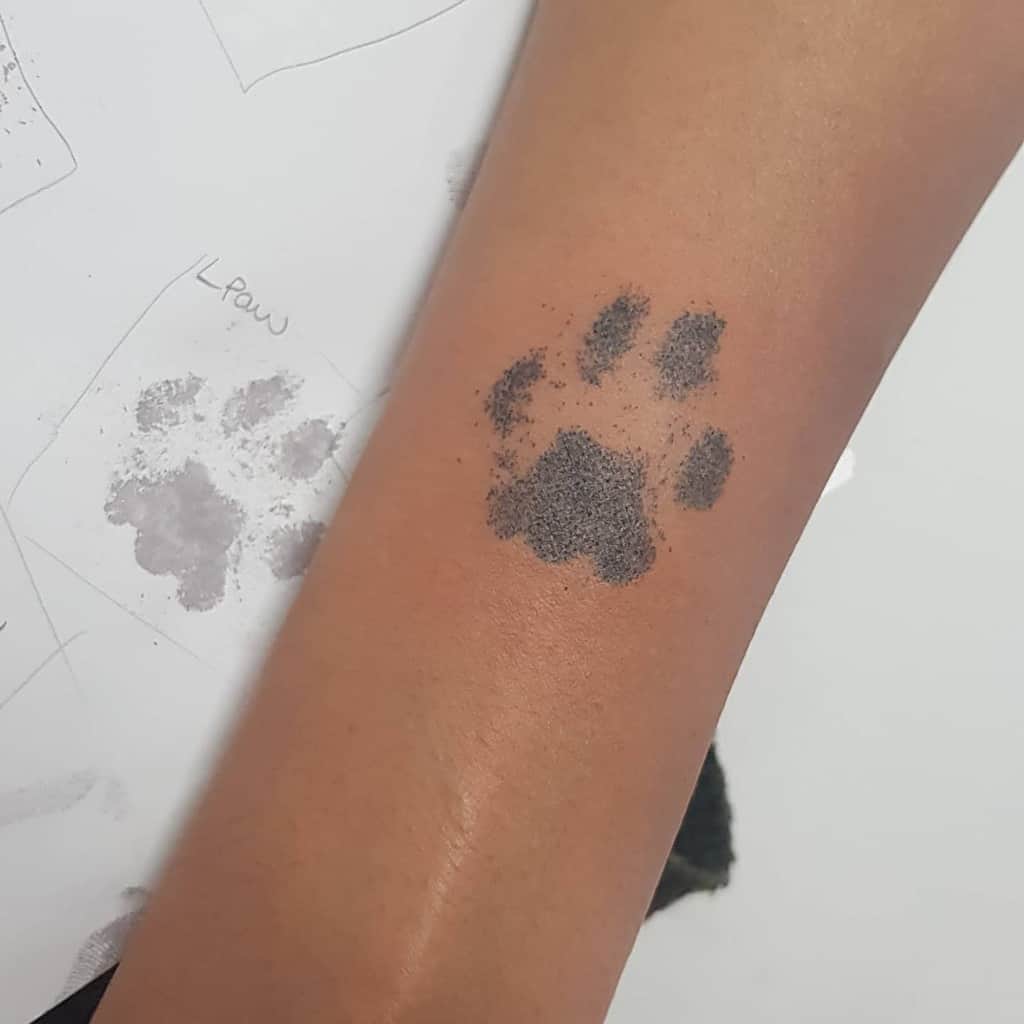 An arm with a black cat paw print stamp on it