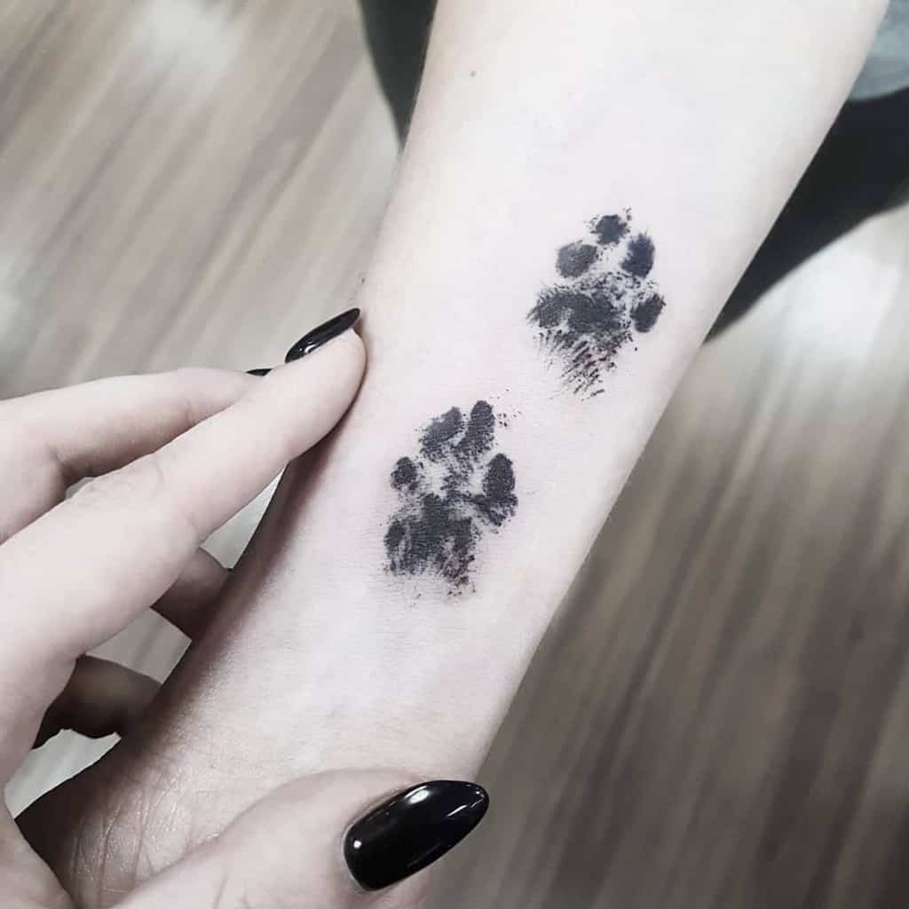 A close-up shot of shaded cat paw print tattoos adorning a person's forearm