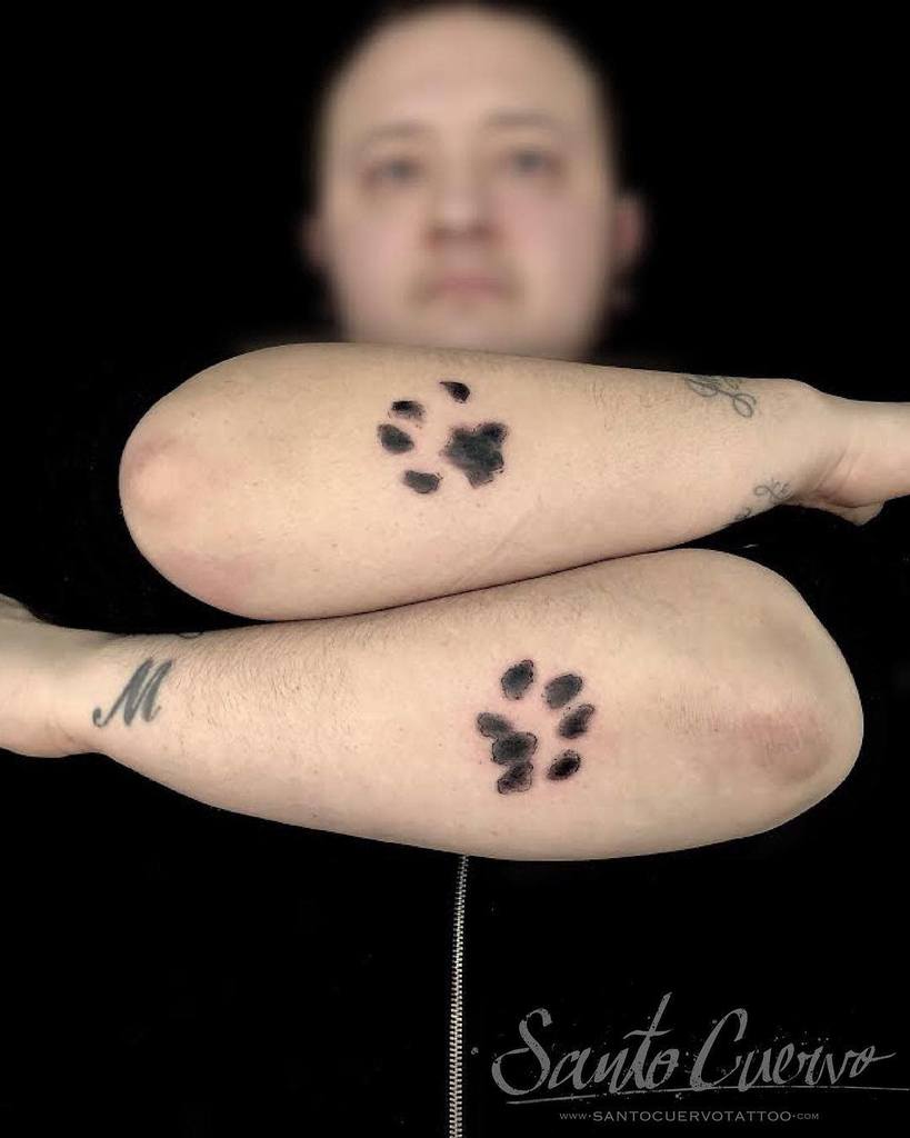 Forearms adorned with shaded black cat paw print tattoos