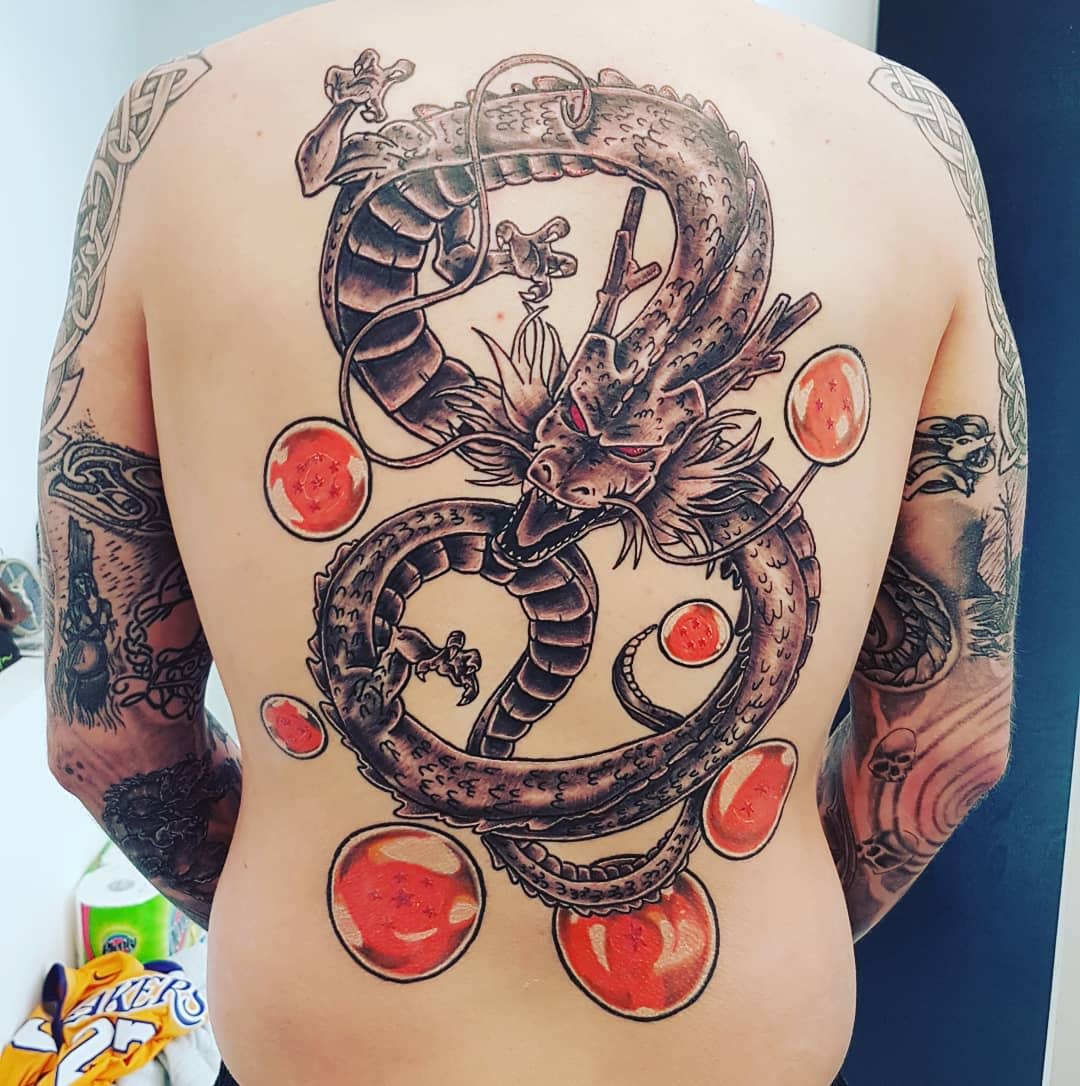 Full back tattoo of Shenron in black and grey, accented by bright red Dragon Balls