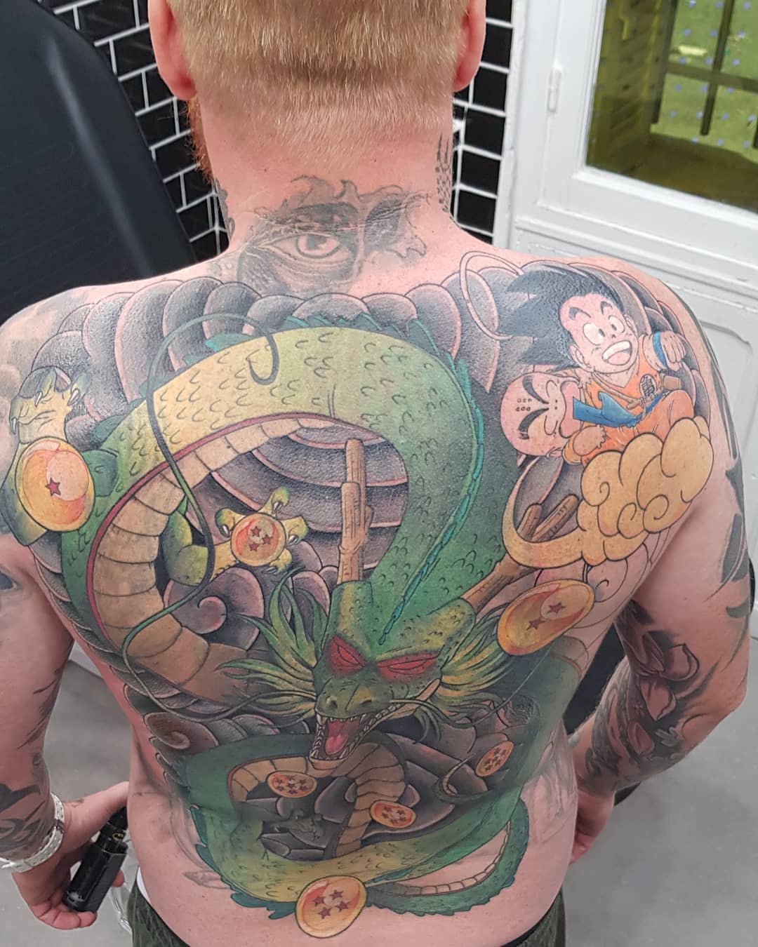 A vibrant full-back tattoo featuring Shenron with Dragon Balls and Goku on the side