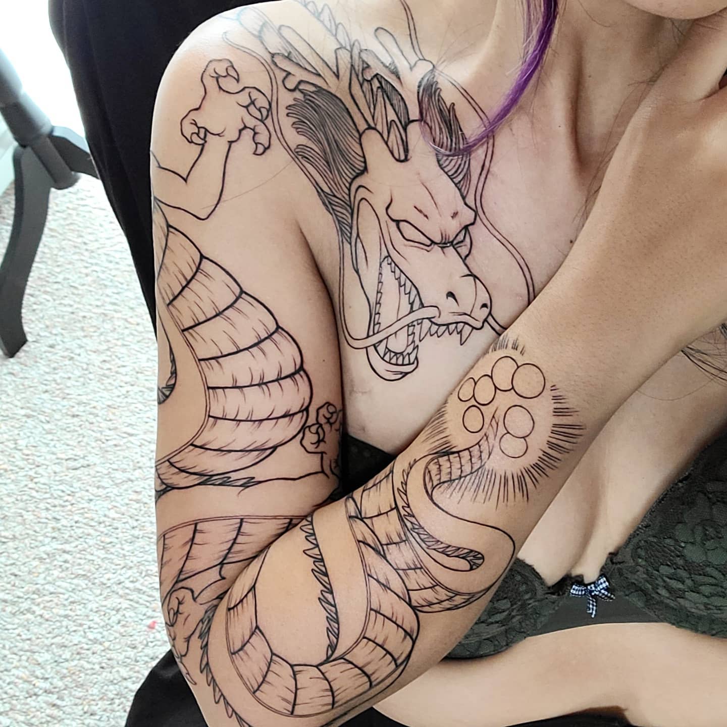 Large outline tattoo of Shenron, covering the arm and chest, with detailed line work