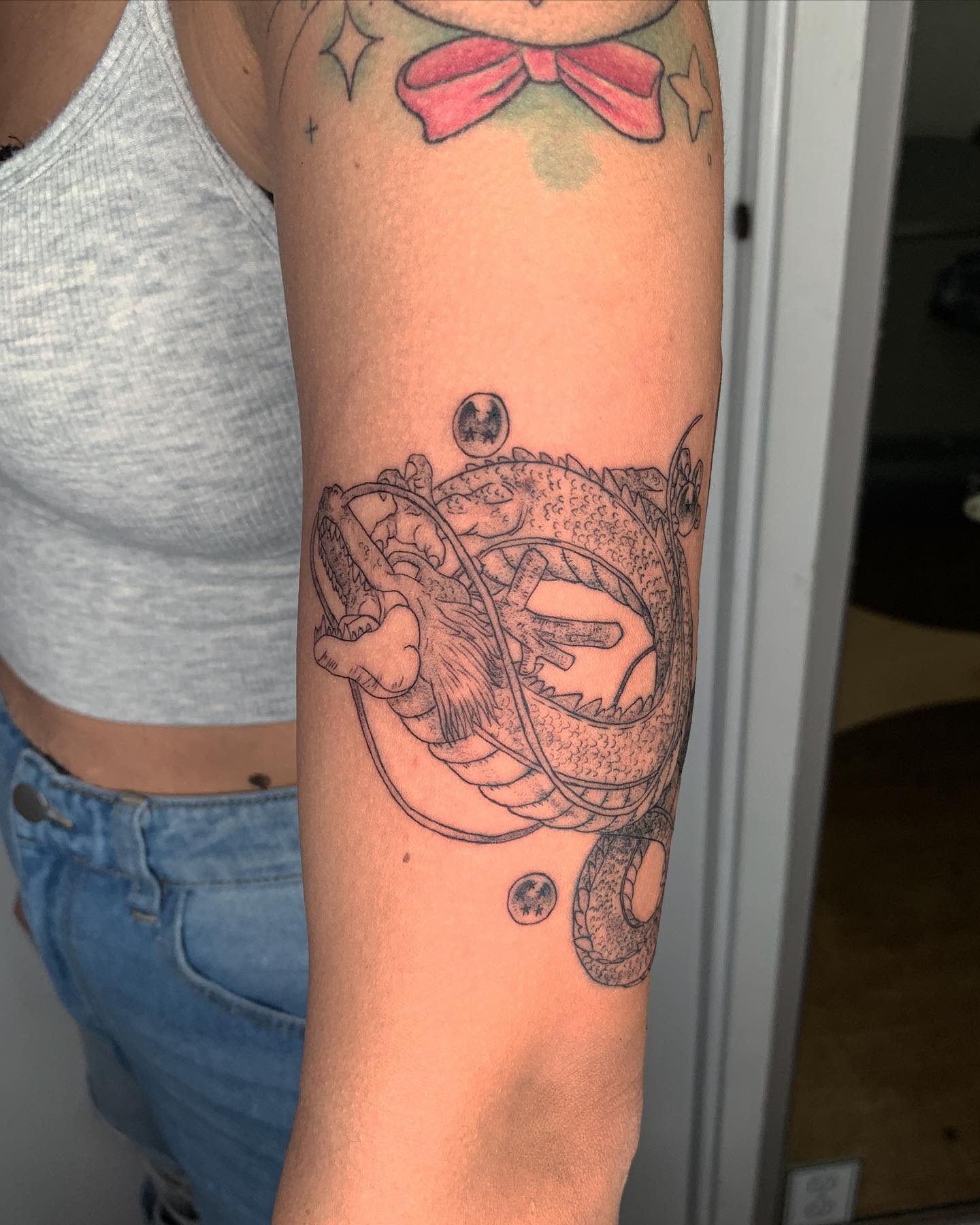 Fine-line Shenron tattoo wrapping around the forearm with detailed Dragon Balls